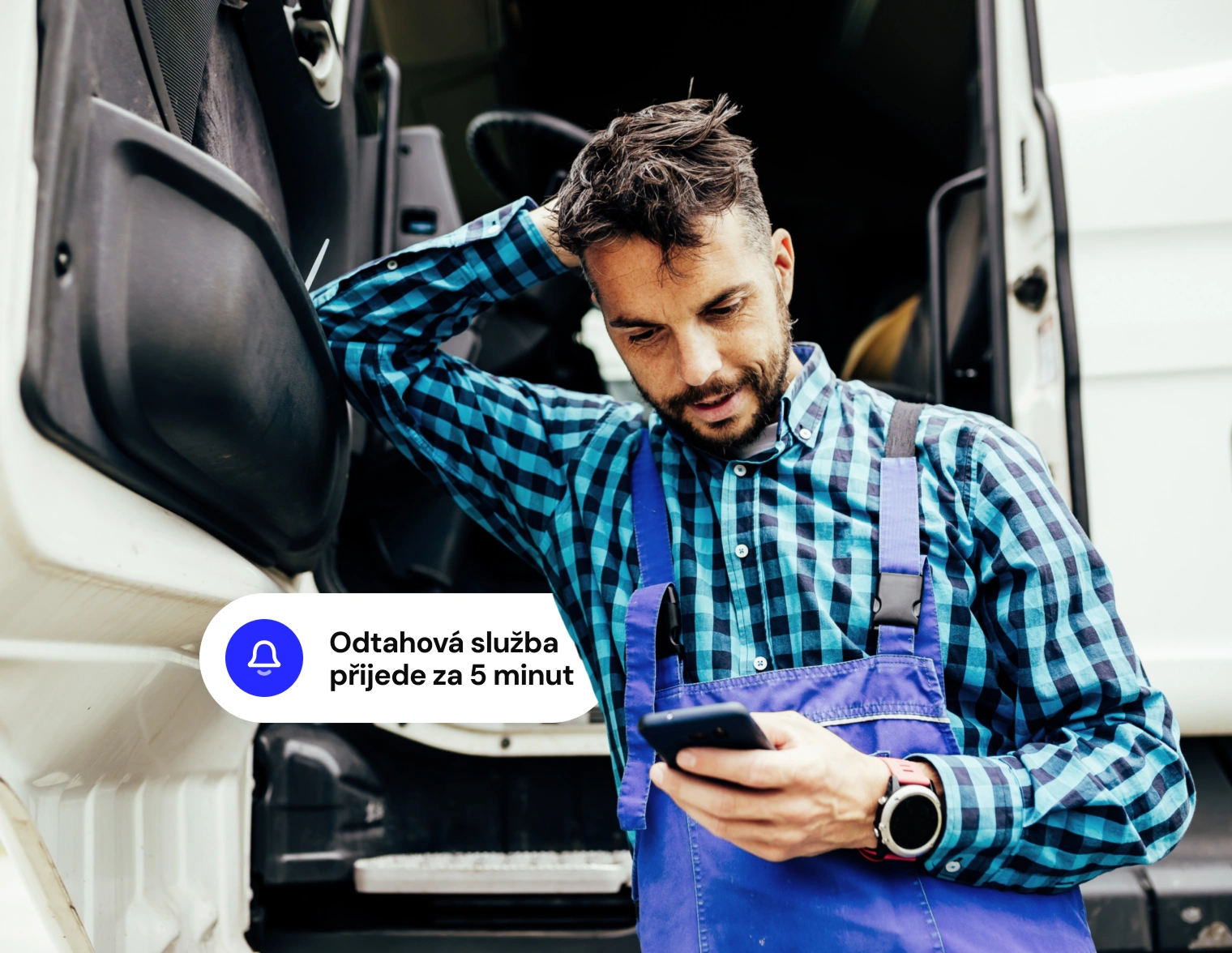 Muž stojí u vozu a sleduje mobil se zprávou - Odtahová služba přijede za 5 minut.