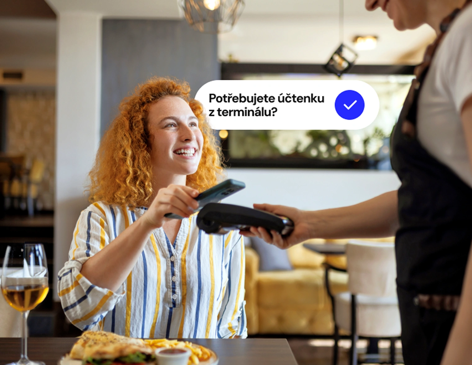 Zákazník platí kartou u platebního terminálu v restauraci.