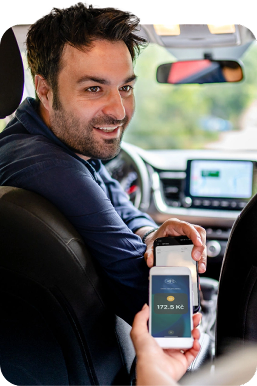 Muž v autě přijímá bezkontaktní platbu mobilem