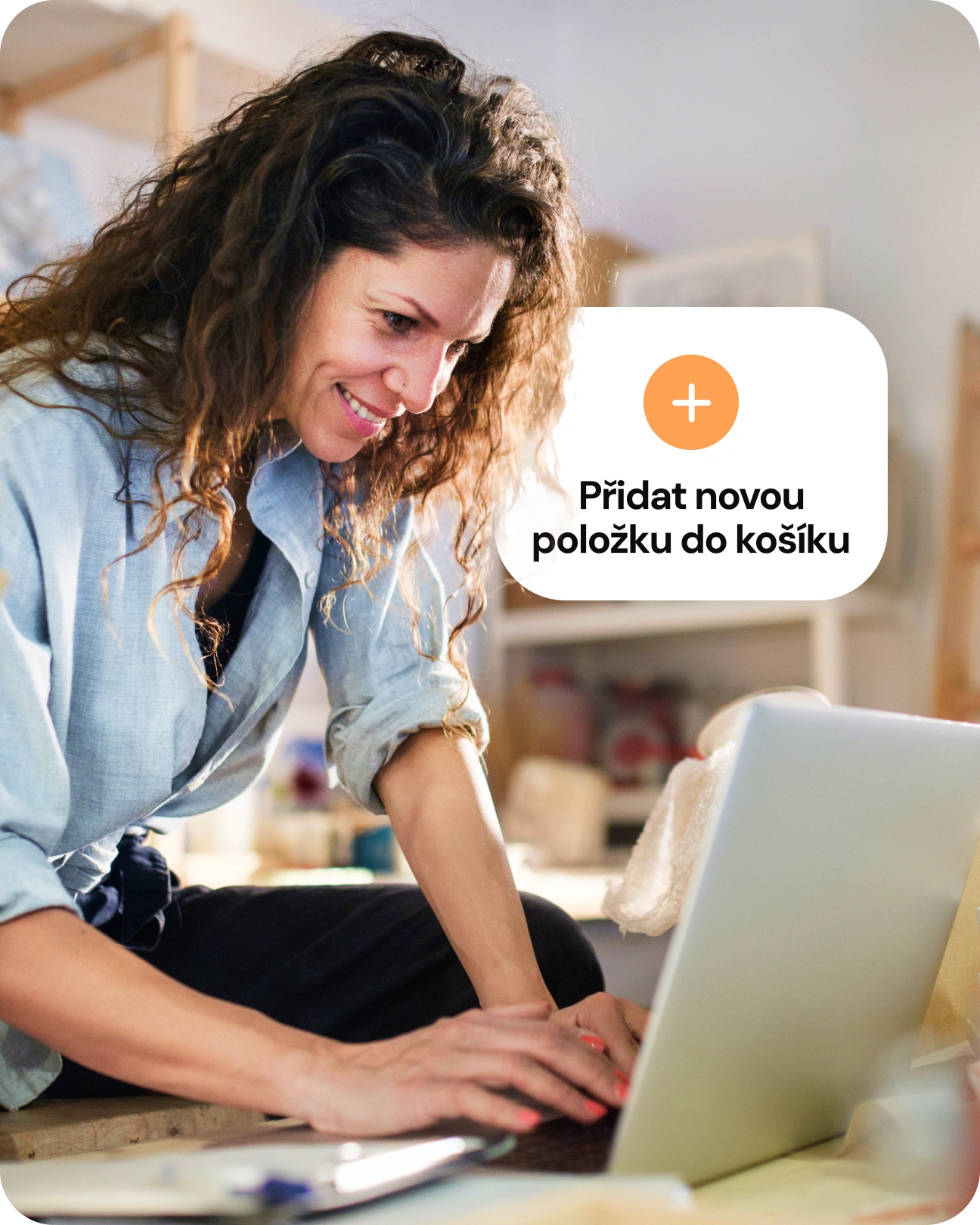 Usmívající se zákazník pracuje na notebooku a přidává novou položku do košíku.
