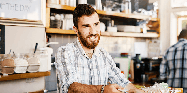 Barista podává zákazníkovi platební terminál u pultu v kavárně.