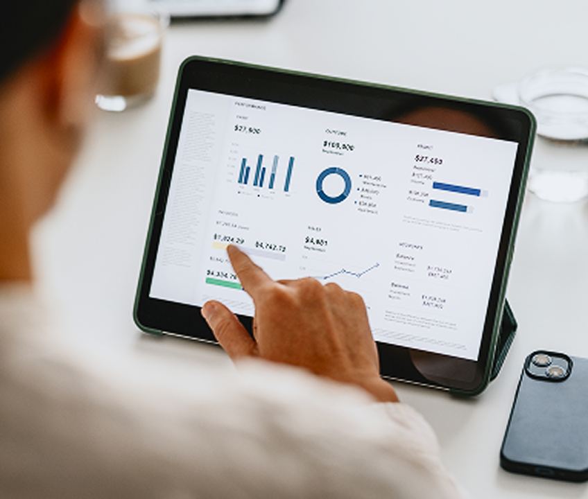 Osoba analyzuje finanční data a grafy na tabletu.